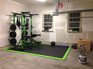 Simple And Clean Heated Garage Gym With Green Weight Bench Set Wall Balls And Yoga Mats