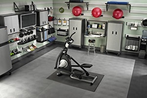 Sleek Looking Black And Silver Themed Garage Gym With Exercise Equipment Tv Elliptical Machine And Stability Balls