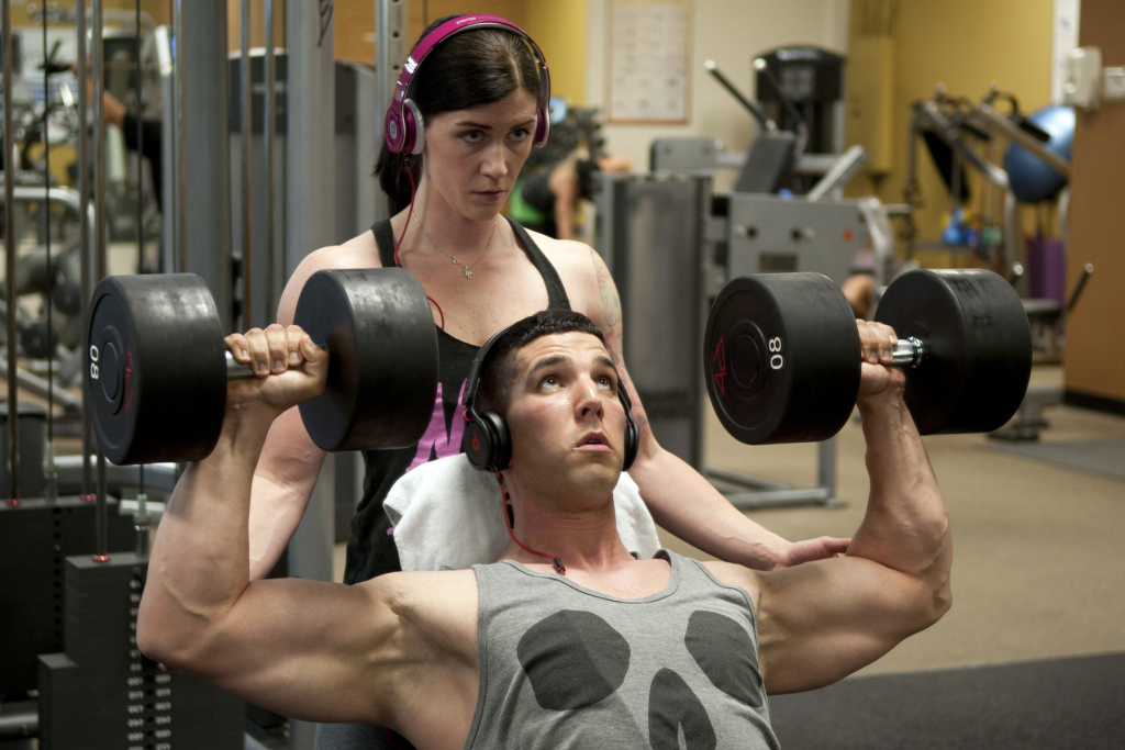 Holly Watters helps her husband Michael, do a seated dumbbell press 